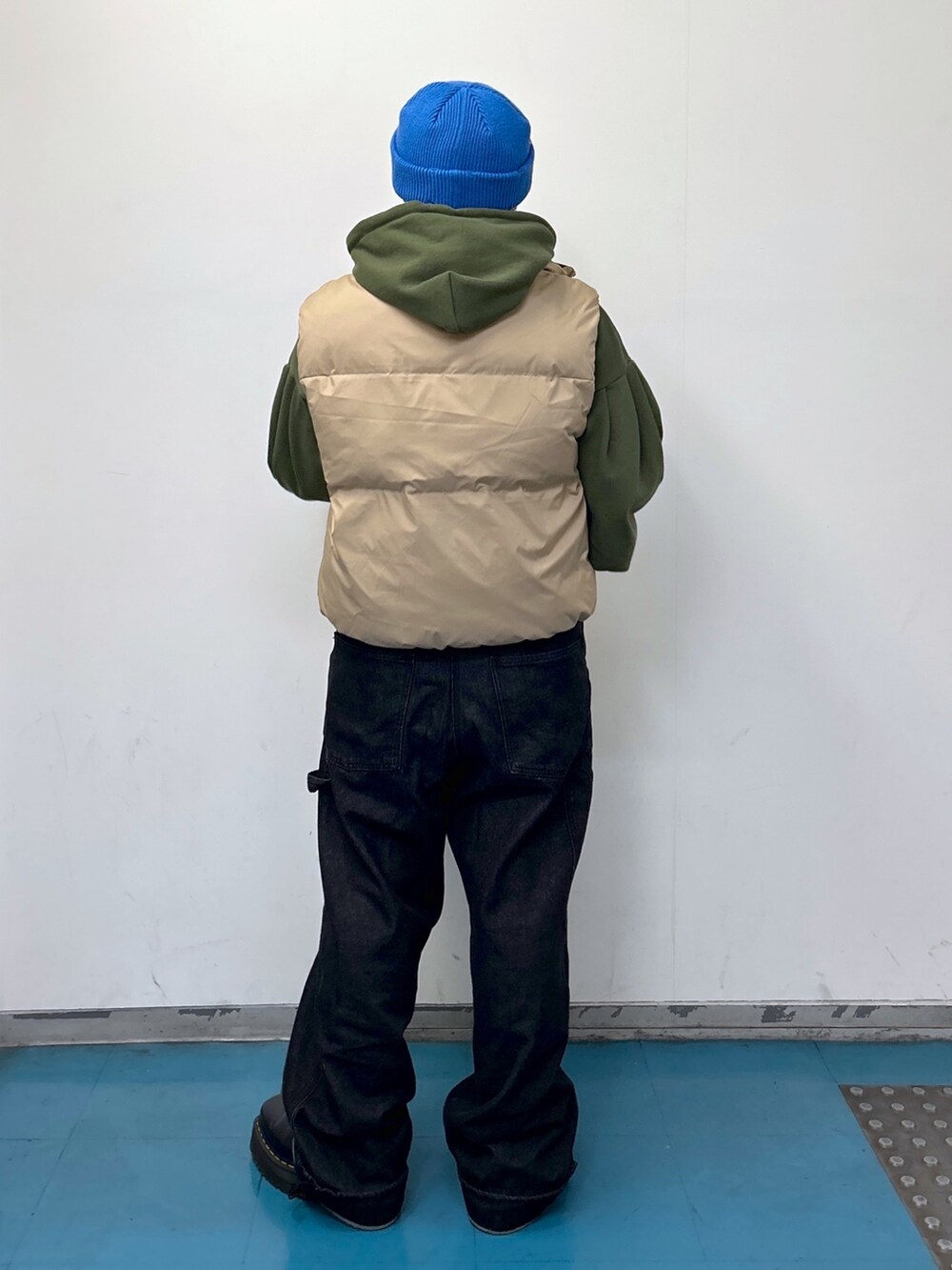 ベージュ系のダウンベスト、グリーン系のパーカー、ブラック系のサロペット/オーバーオールを着用したレディースの冬コーディネートの3枚目の写真