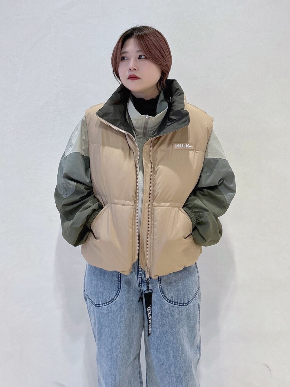 ブルー系のデニムパンツ、グリーン系のハンドバッグ、ブラック系のブーツを着用したレディースの冬コーディネートの5枚目の写真