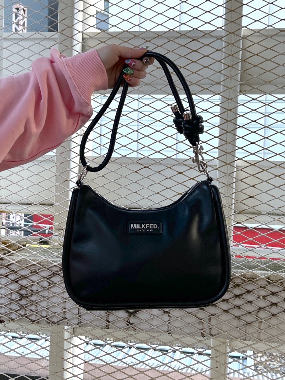 ピンク系のスウェット、ブラック系のショルダーバッグ、ブラック系のブーツを着用したレディースの冬コーディネートの6枚目の写真