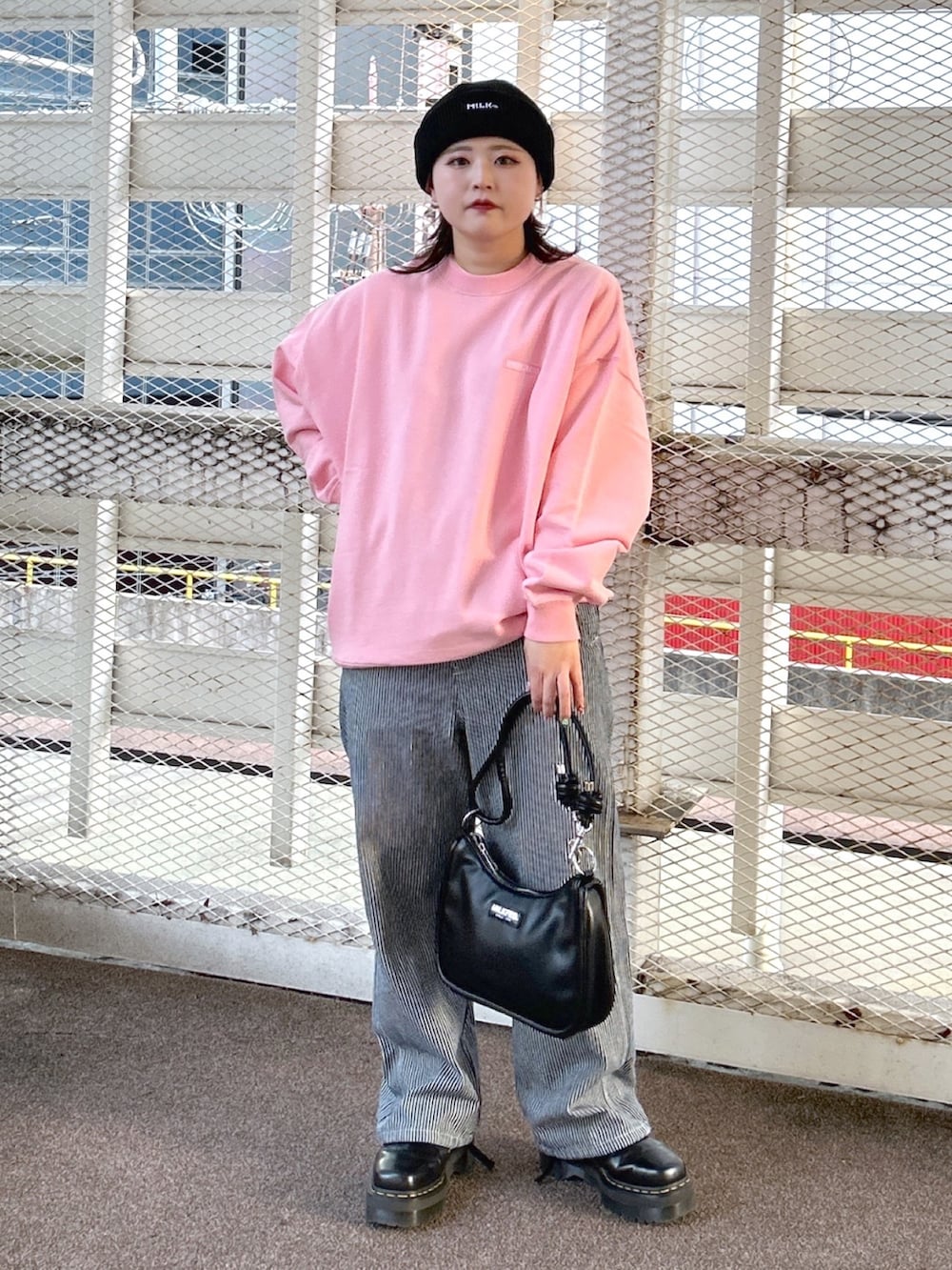 ピンク系のスウェット、ブラック系のショルダーバッグ、ブラック系のブーツを着用したレディースの冬コーディネートの2枚目の写真