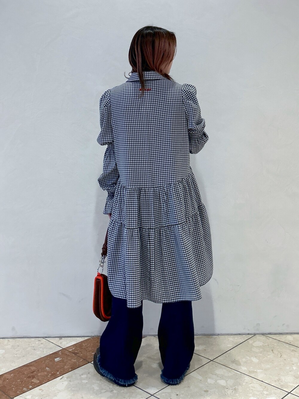 ブラック系のワンピース、ブルー系のデニムパンツ、ブラウン系のショルダーバッグを着用したレディースの春コーディネートの3枚目の写真