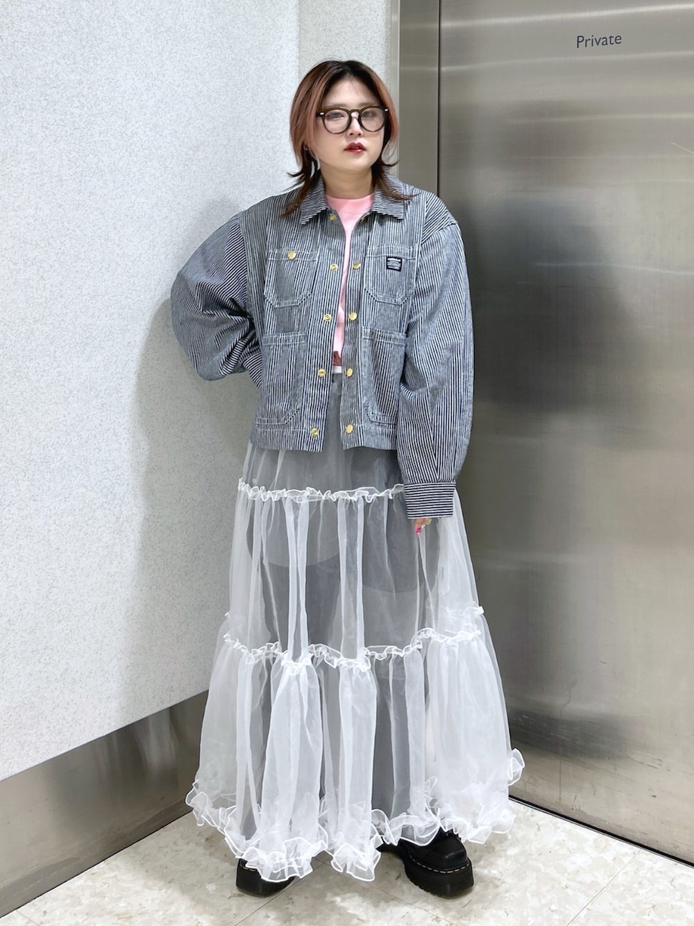 ホワイト系のスカート、ブラック系のデニムパンツ、ブラック系のブーツを着用したレディースの春コーディネートの3枚目の写真