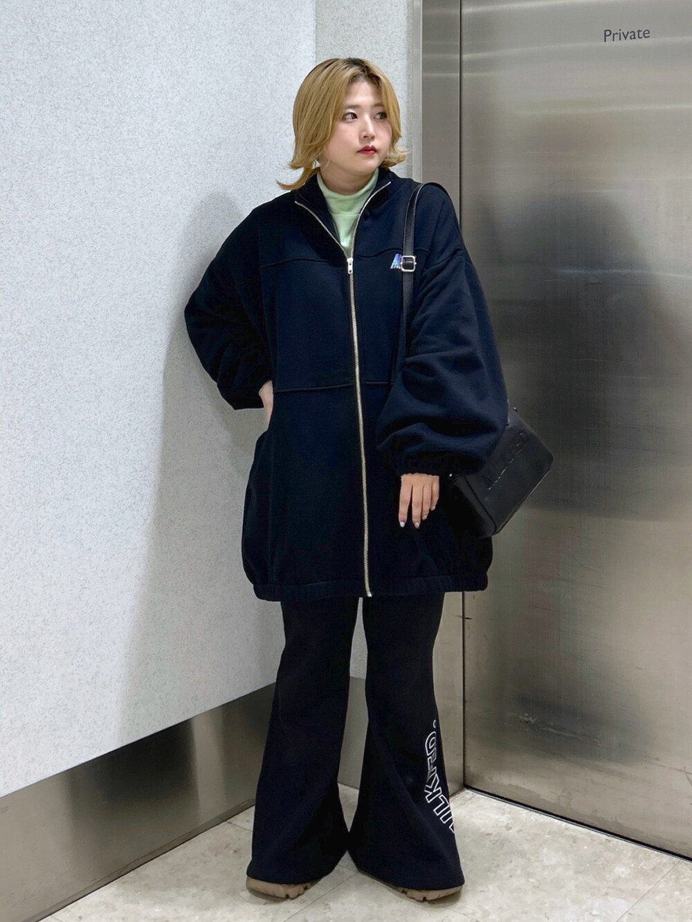 ブラック系のスウェット、ブラック系のボストンバッグ、グリーン系のTシャツ/カットソーを着用したレディースの秋コーディネートの2枚目の写真