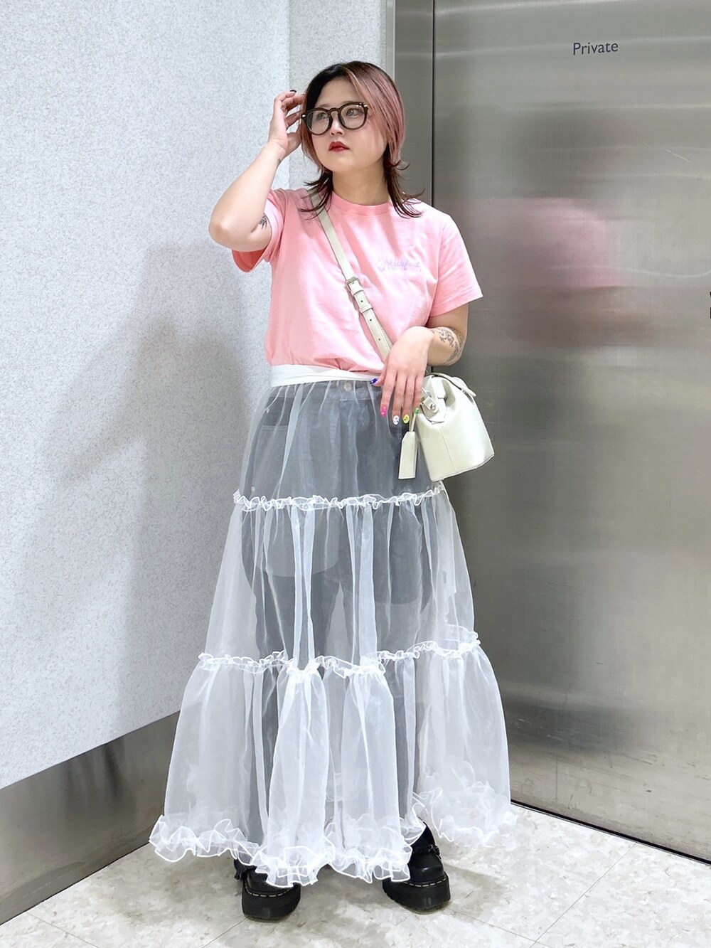 ピンク系のTシャツ/カットソー、ブラック系のデニムパンツ、ホワイト系のスカートを着用したレディースの春コーディネートの2枚目の写真