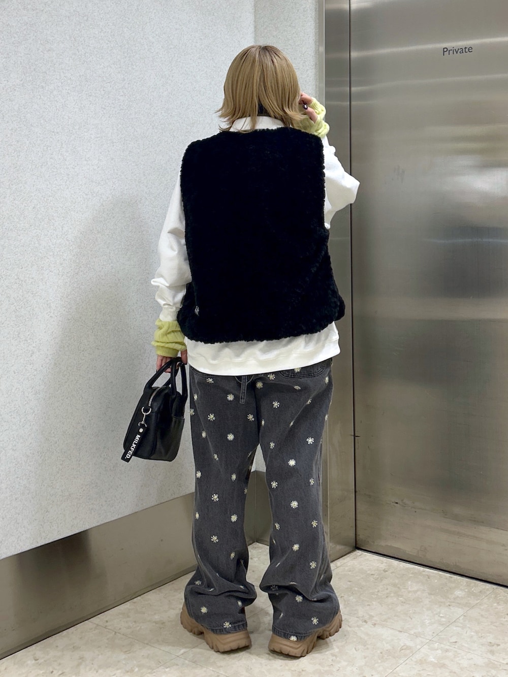 ブラック系のベスト、ホワイト系のスウェット、ブラック系のボストンバッグを着用したレディースの秋コーディネートの3枚目の写真