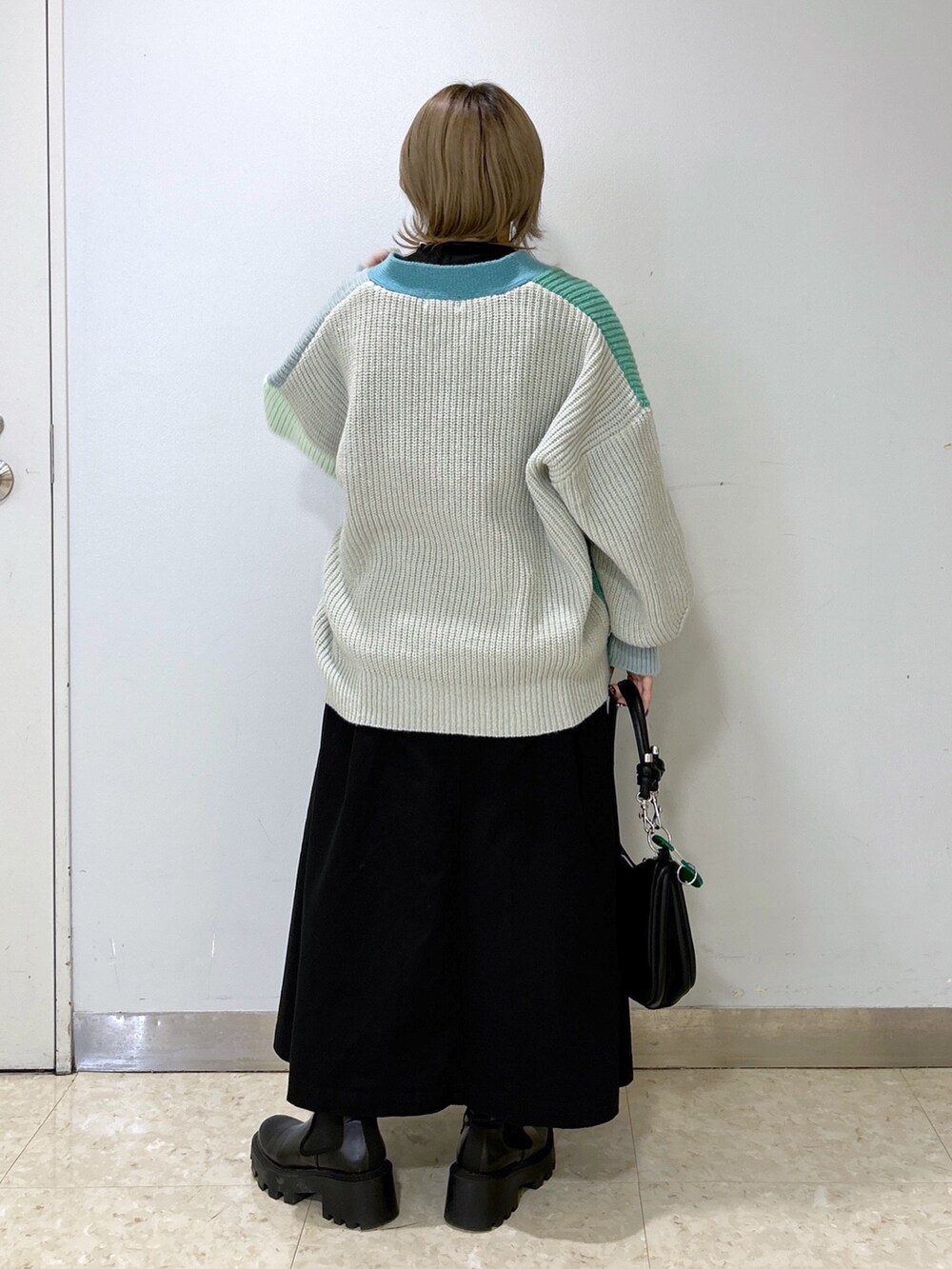 グリーン系のカーディガン/ボレロ、ブラック系のその他トップス、ブラック系のジャンパースカートを着用したレディースの秋コーディネートの3枚目の写真