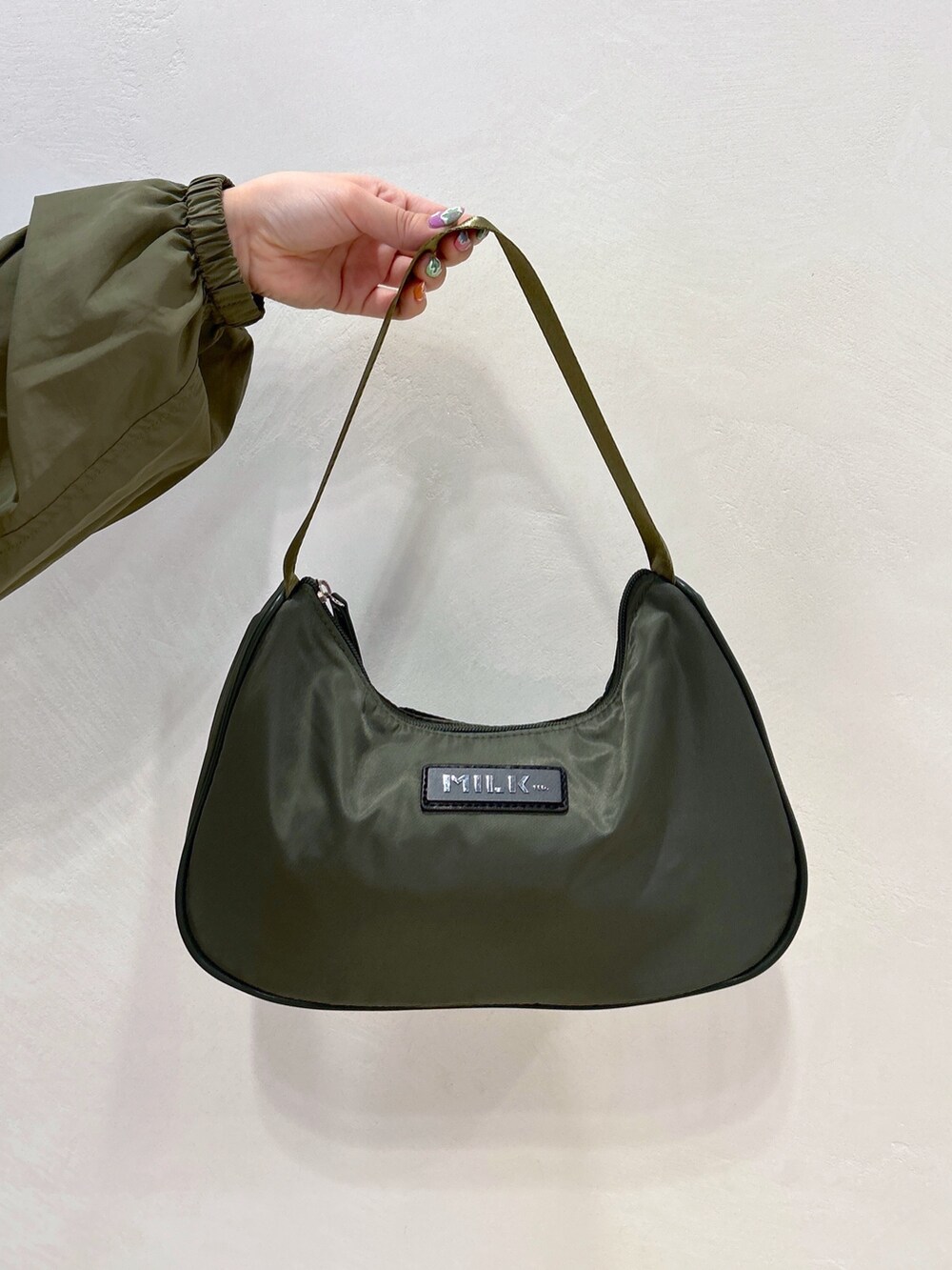 ブルー系のデニムパンツ、グリーン系のハンドバッグ、ブラック系のブーツを着用したレディースの冬コーディネートの9枚目の写真