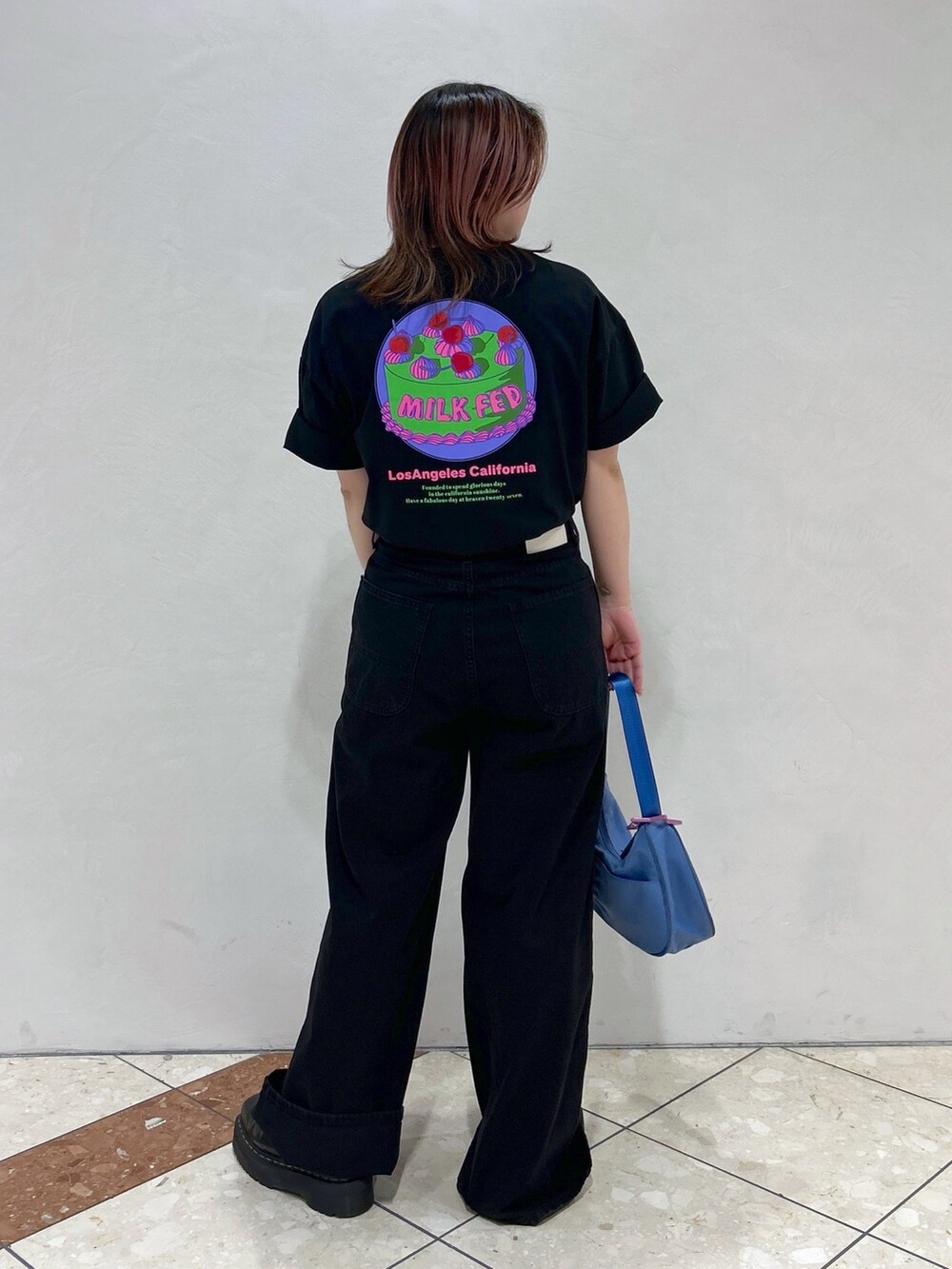 ブラック系のTシャツ/カットソー、ブルー系のハンドバッグ、ブラック系のブーツを着用したレディースの春コーディネートの3枚目の写真