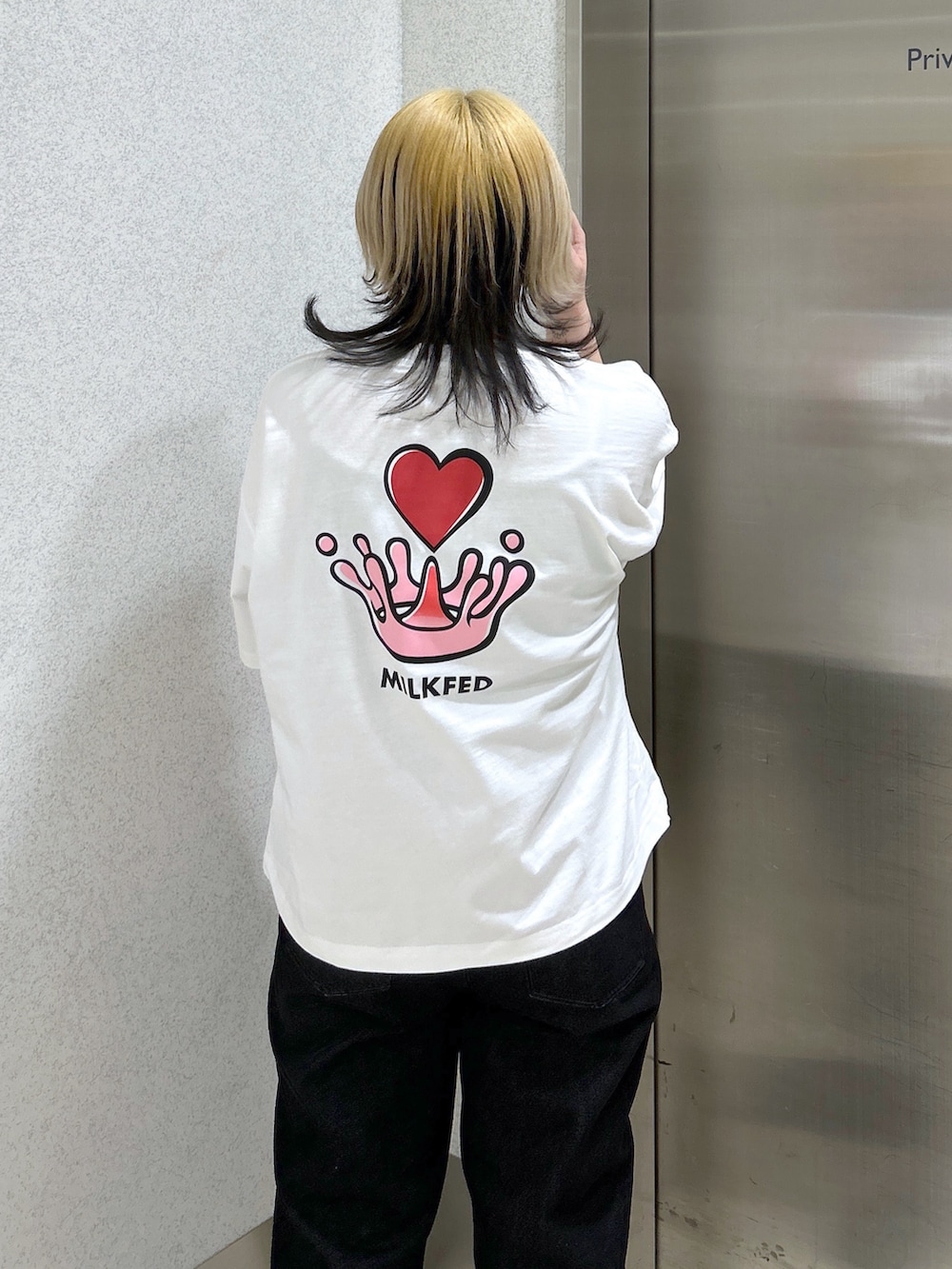 ブラック系のデニムパンツ、ホワイト系のショルダーバッグ、ブラック系のブーツを着用したレディースの春コーディネートの5枚目の写真