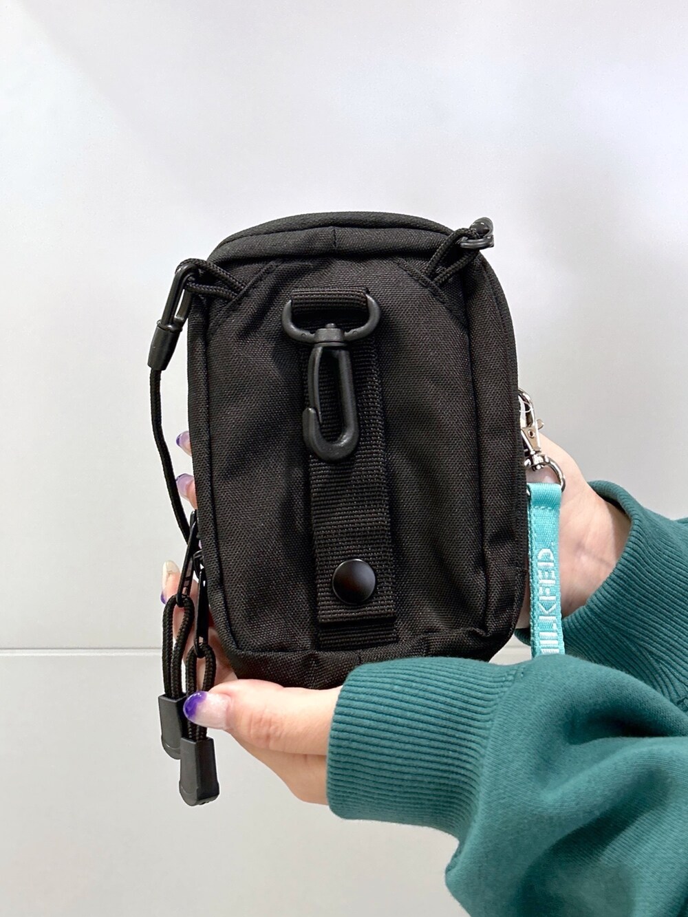 グリーン系のパーカー、グリーン系のショルダーバッグ、ブラック系のスカートを着用したレディースの秋コーディネートの5枚目の写真