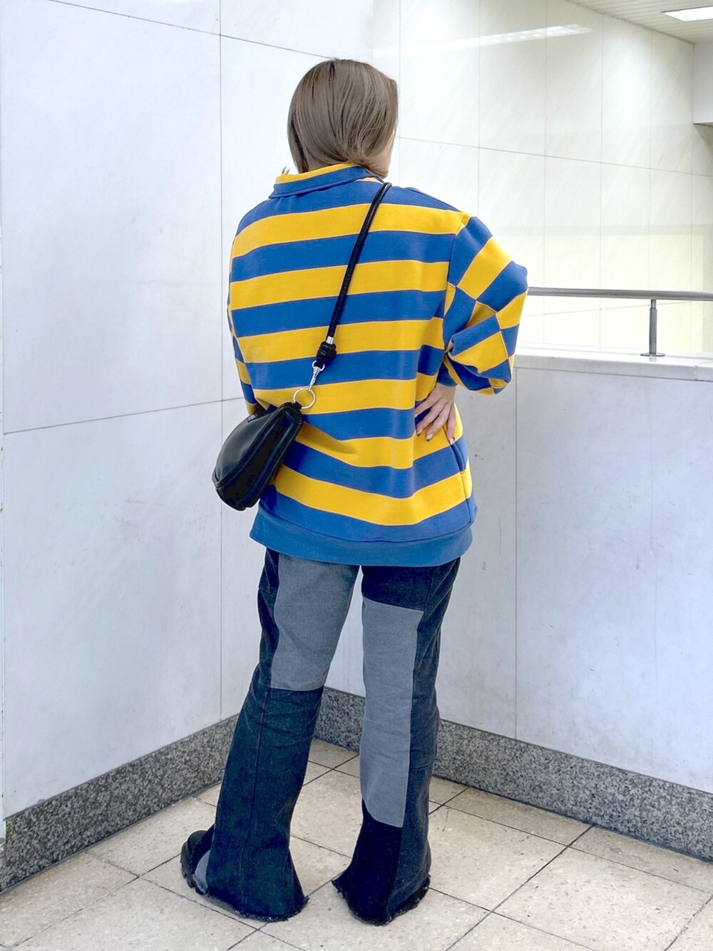 イエロー系のスウェット、ブラック系のデニムパンツ、ブラック系のショルダーバッグを着用したレディースの冬コーディネートの3枚目の写真