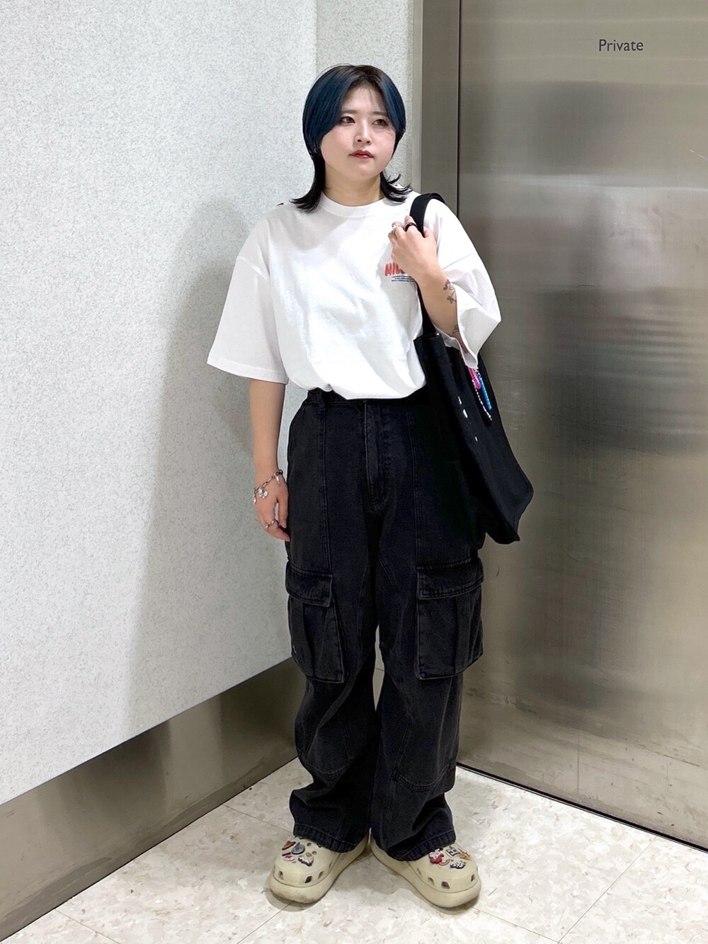 ブラック系のカーゴパンツ、ブラック系のショルダーバッグ、ホワイト系のTシャツ/カットソーを着用したレディースの夏コーディネートの2枚目の写真