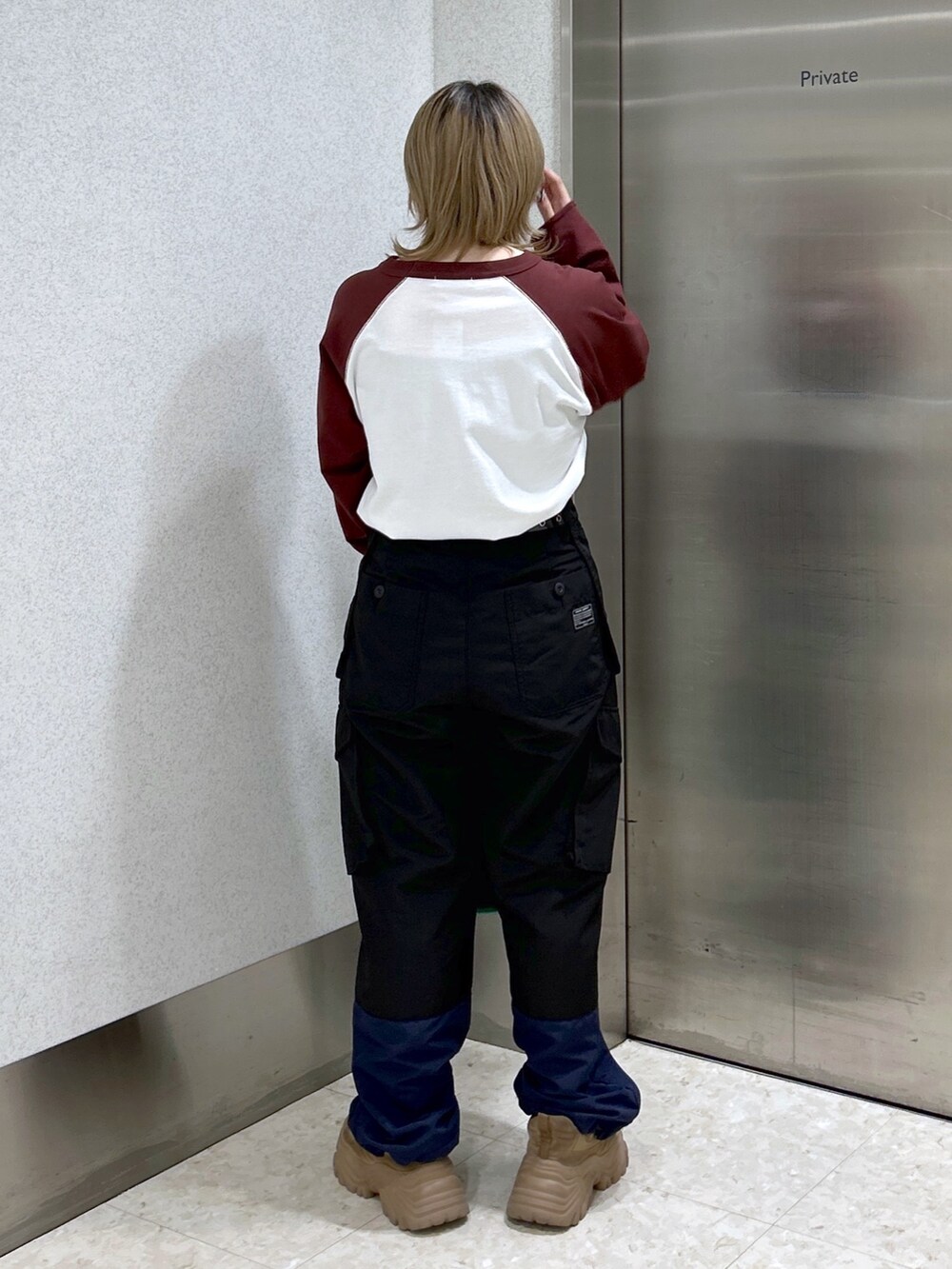 ブラウン系のTシャツ/カットソー、ブラック系のカーゴパンツ、グリーン系のショルダーバッグを着用したレディースの冬コーディネートの3枚目の写真