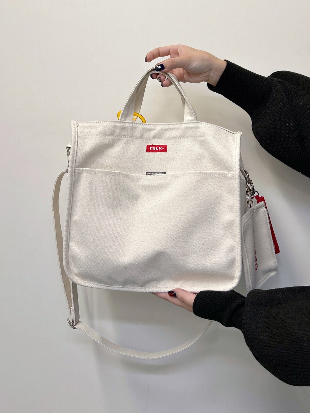 ブラック系のニット/セーター、ブラック系のデニムパンツ、レッド系のショルダーバッグを着用したレディースの秋コーディネートの5枚目の写真