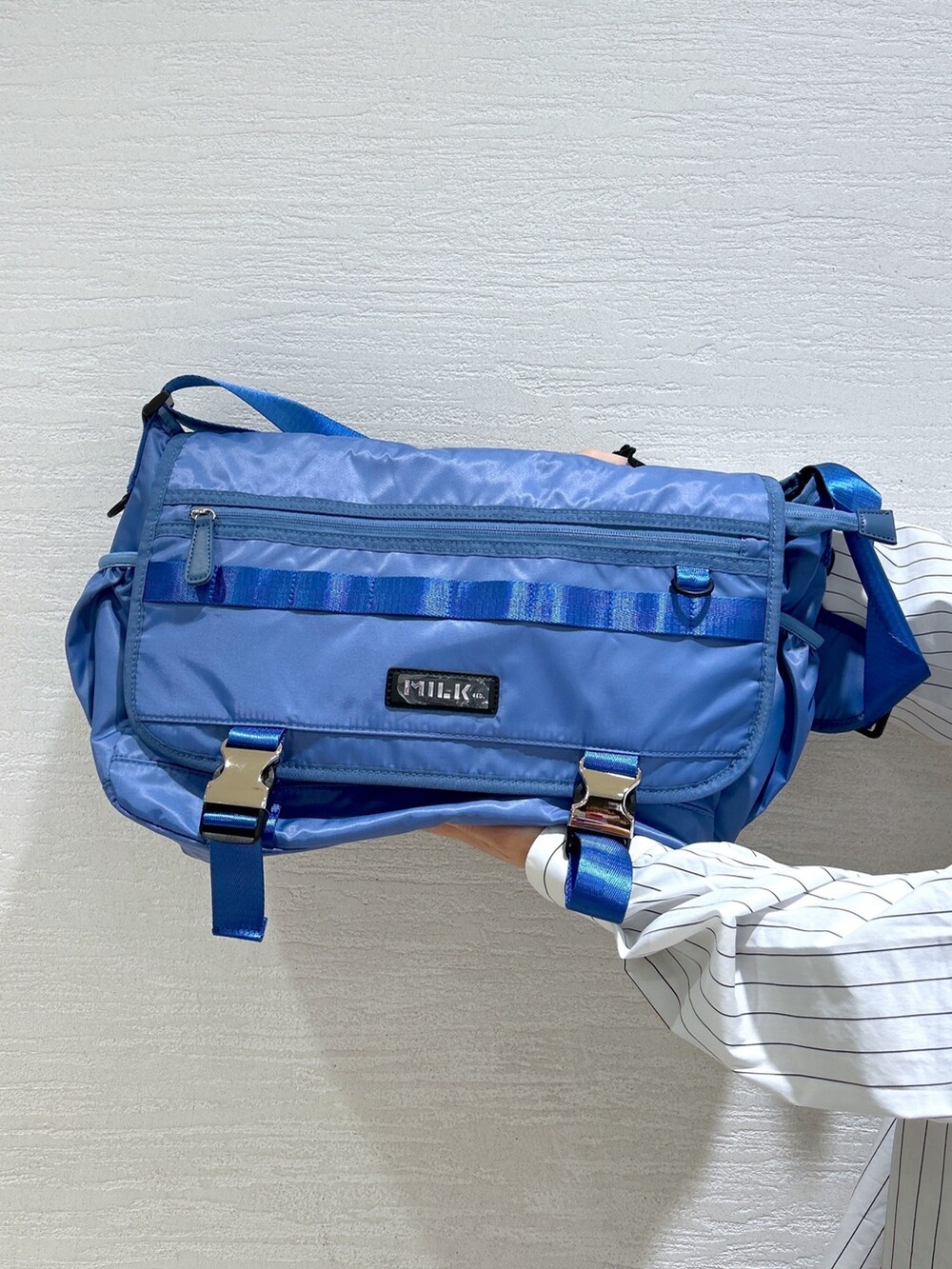 ホワイト系のシャツ/ブラウス、ブルー系のメッセンジャーバッグ、ブラック系のスウェットパンツを着用したレディースの冬コーディネートの9枚目の写真