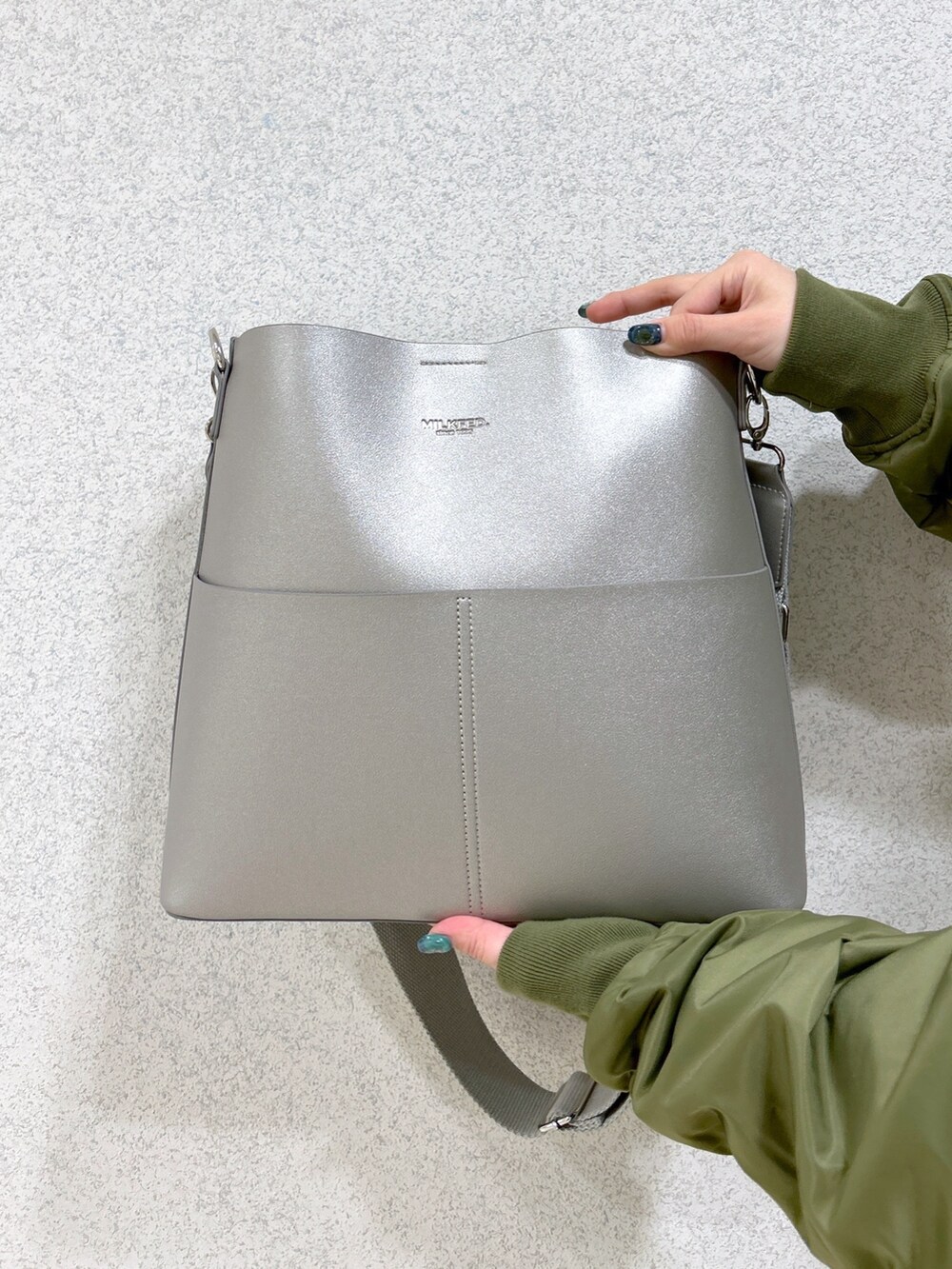 グレー系のワンピース、グリーン系のMA-1、シルバー系のショルダーバッグを着用したレディースの冬コーディネートの5枚目の写真