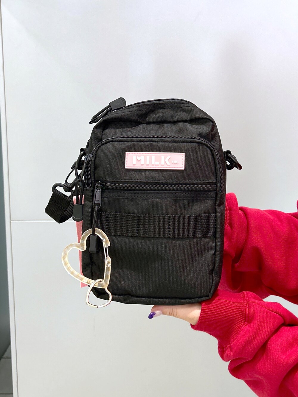 レッド系のスウェット、ピンク系のショルダーバッグ、ブラック系のデニムパンツを着用したレディースの秋コーディネートの4枚目の写真