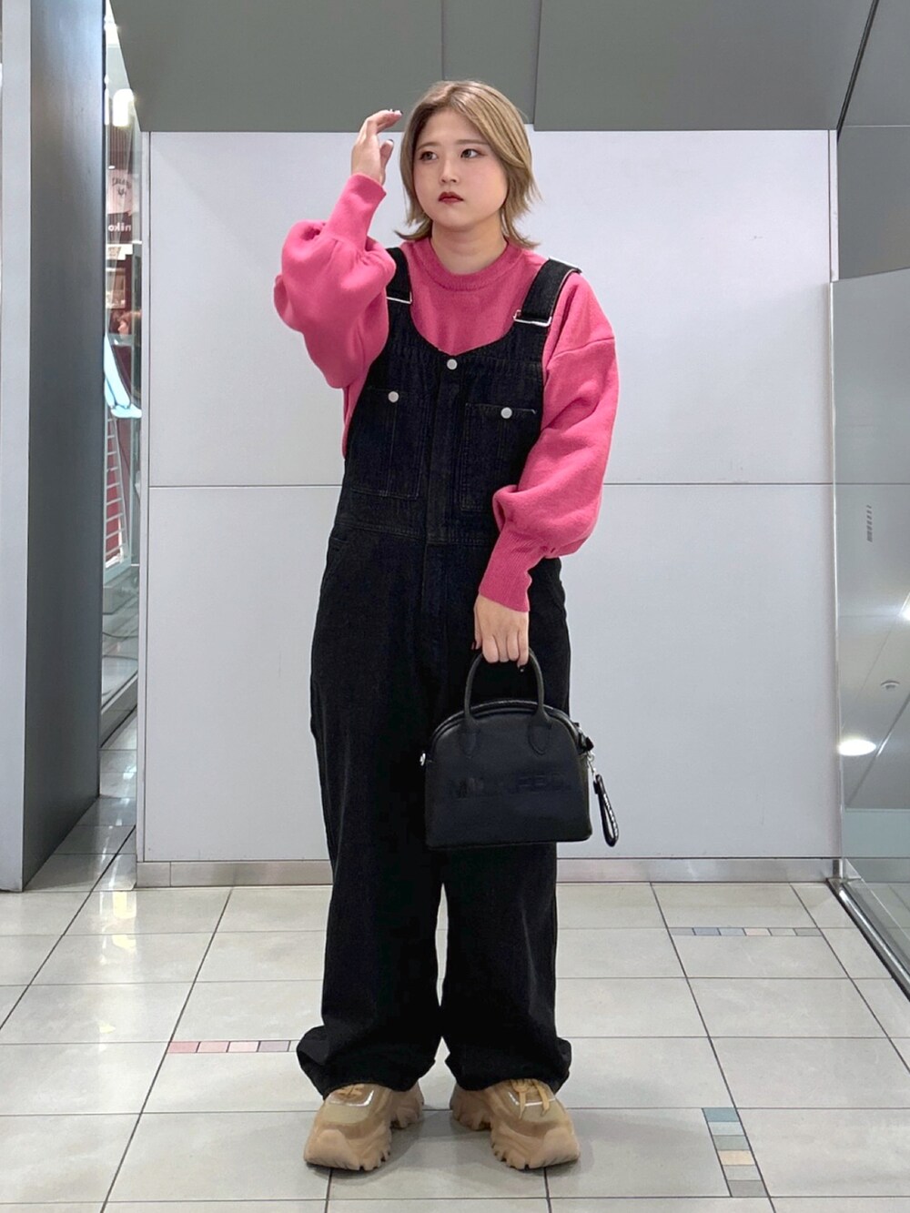 ピンク系のニット/セーター、ブラック系のサロペット/オーバーオール、ブラック系のボストンバッグを着用したレディースの秋コーディネートの2枚目の写真