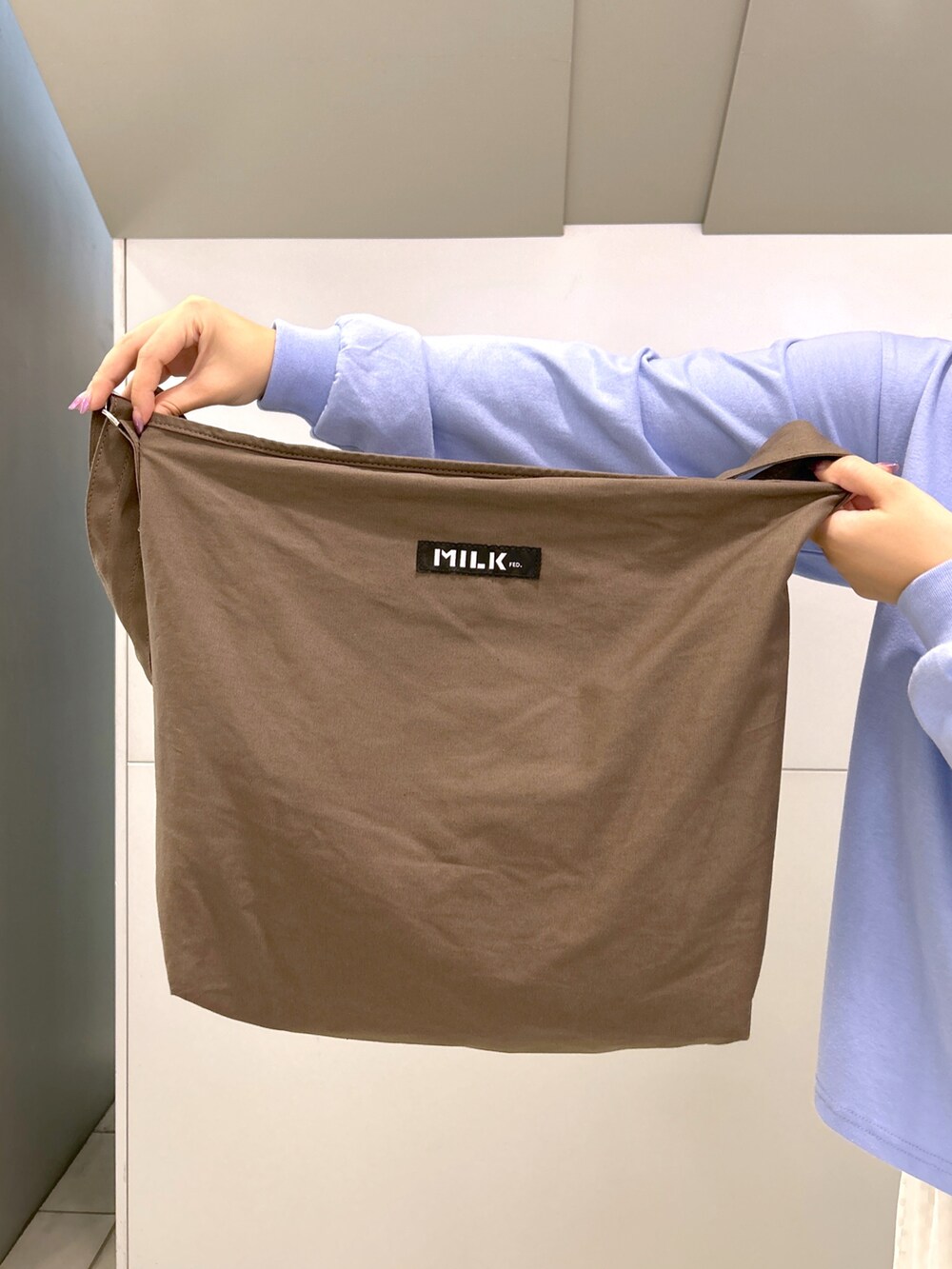 ブルー系のTシャツ/カットソー、ブラウン系のショルダーバッグ、ホワイト系のスカートを着用したレディースの夏コーディネートの5枚目の写真