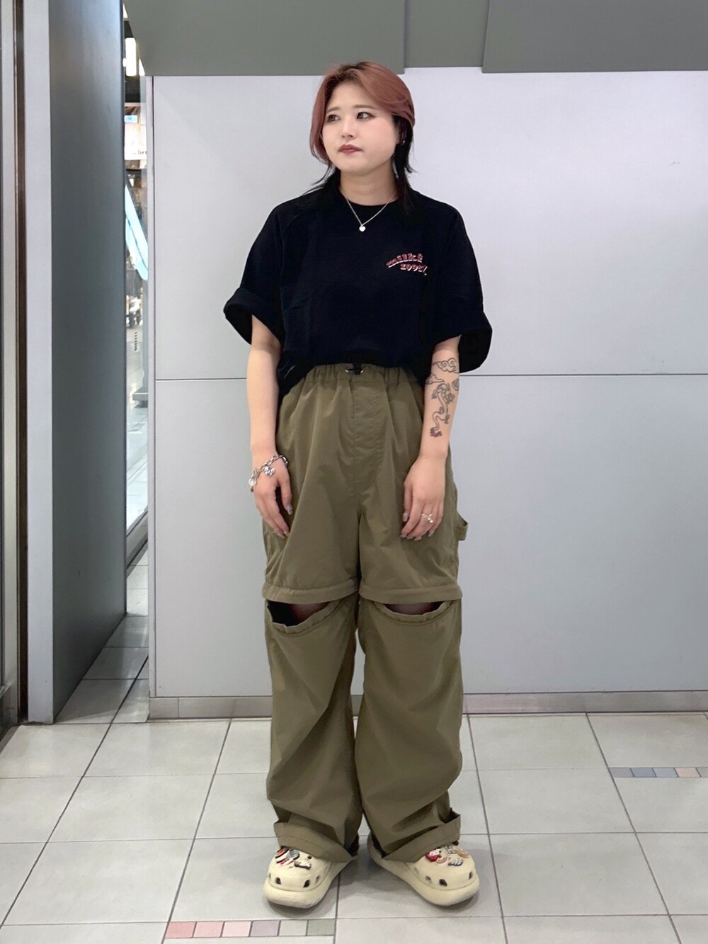 グリーン系のその他パンツ、ブラック系のTシャツ/カットソー、ベージュ系のサンダルを着用したレディースの夏コーディネートの2枚目の写真