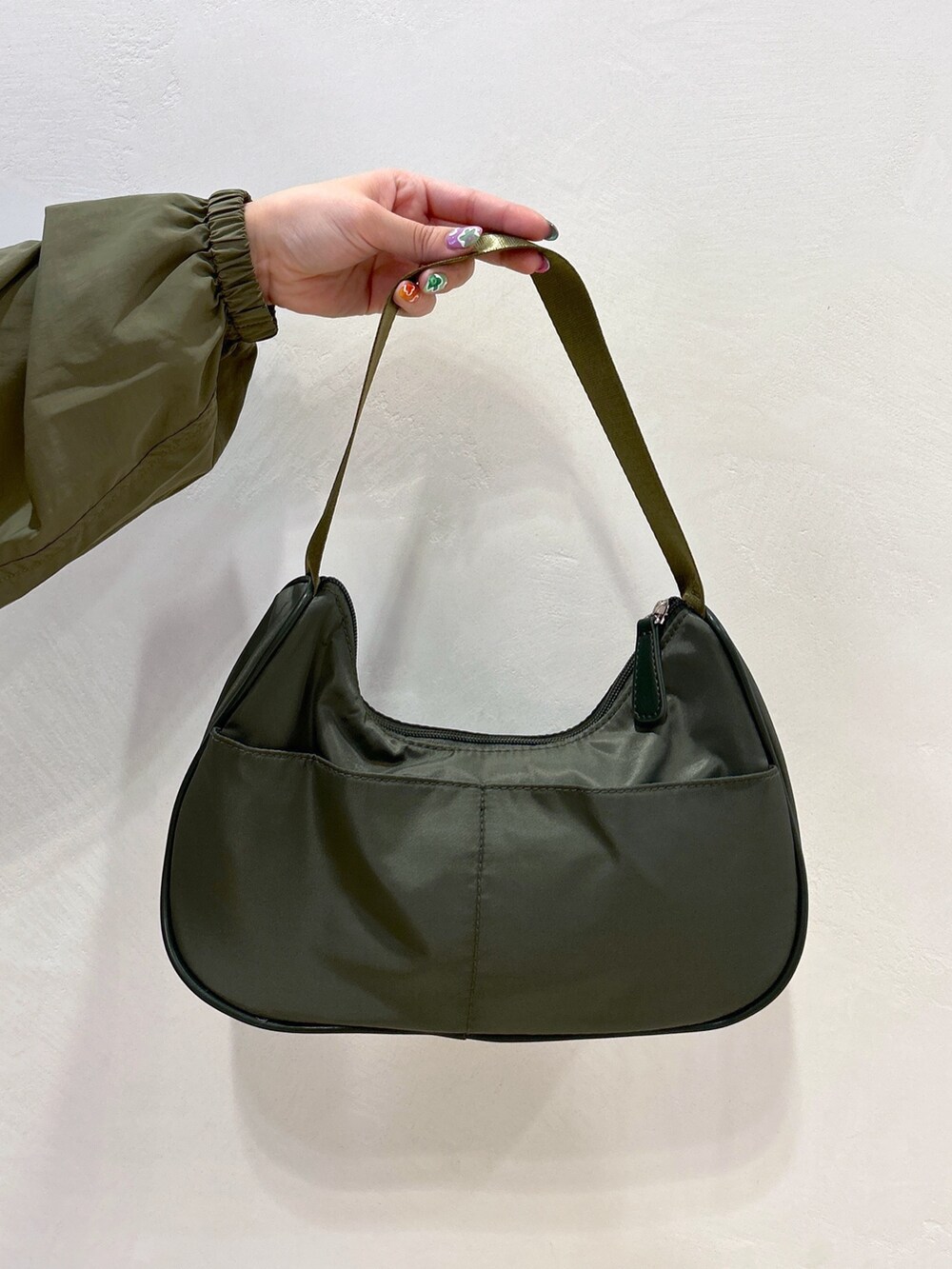 ブルー系のデニムパンツ、グリーン系のハンドバッグ、ブラック系のブーツを着用したレディースの冬コーディネートの10枚目の写真