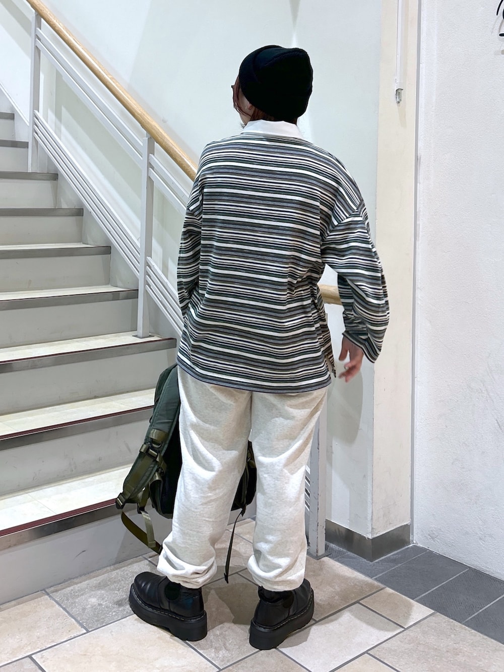 グリーン系のポロシャツ、ベージュ系のスウェットパンツ、グリーン系のバックパック/リュックを着用したレディースの冬コーディネートの6枚目の写真