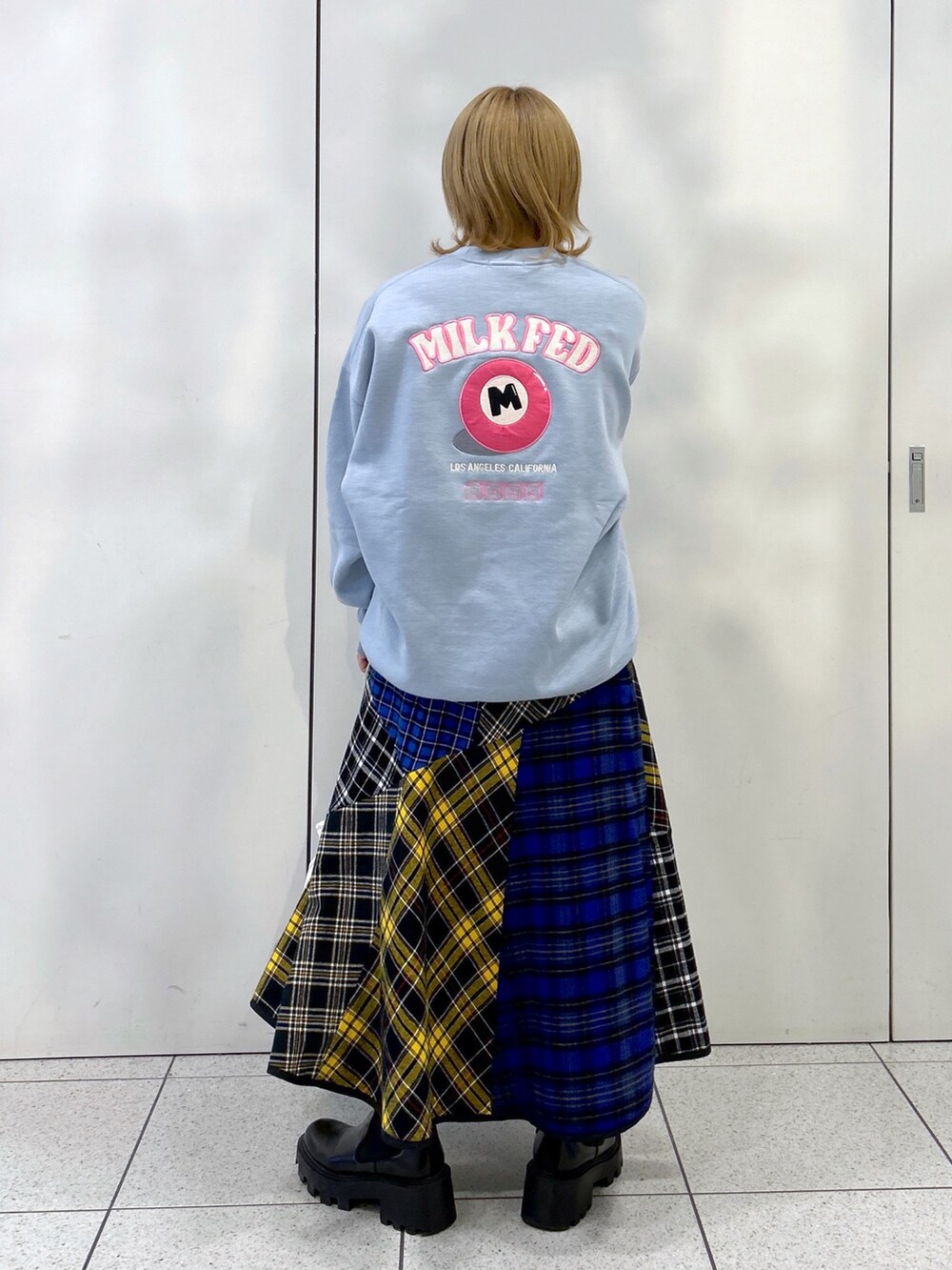 ブルー系のスウェット、ブルー系のトートバッグ、ブラック系のスカートを着用したレディースの秋コーディネートの3枚目の写真