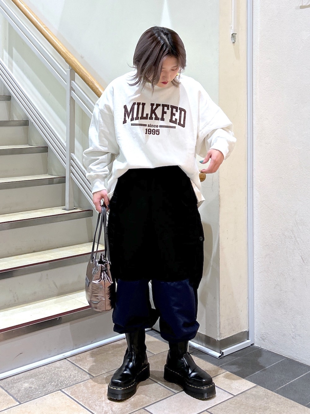 ブラック系のカーゴパンツ、シルバー系のショルダーバッグ、ブラック系のブーツを着用したレディースの冬コーディネートの2枚目の写真