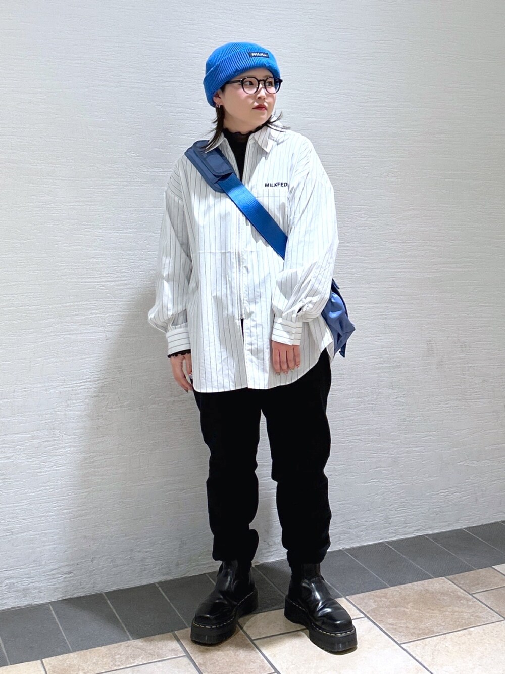 ホワイト系のシャツ/ブラウス、ブルー系のメッセンジャーバッグ、ブラック系のスウェットパンツを着用したレディースの冬コーディネートの2枚目の写真