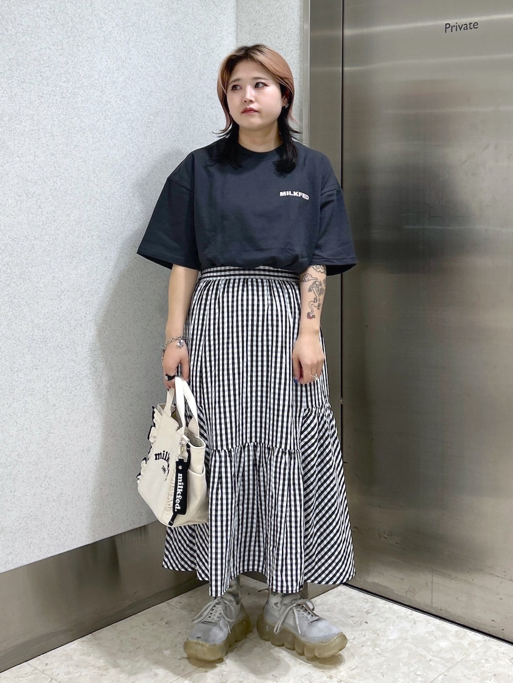 グレー系のTシャツ/カットソー、ブラック系のスカート、ホワイト系のショルダーバッグを着用したレディースの夏コーディネートの2枚目の写真