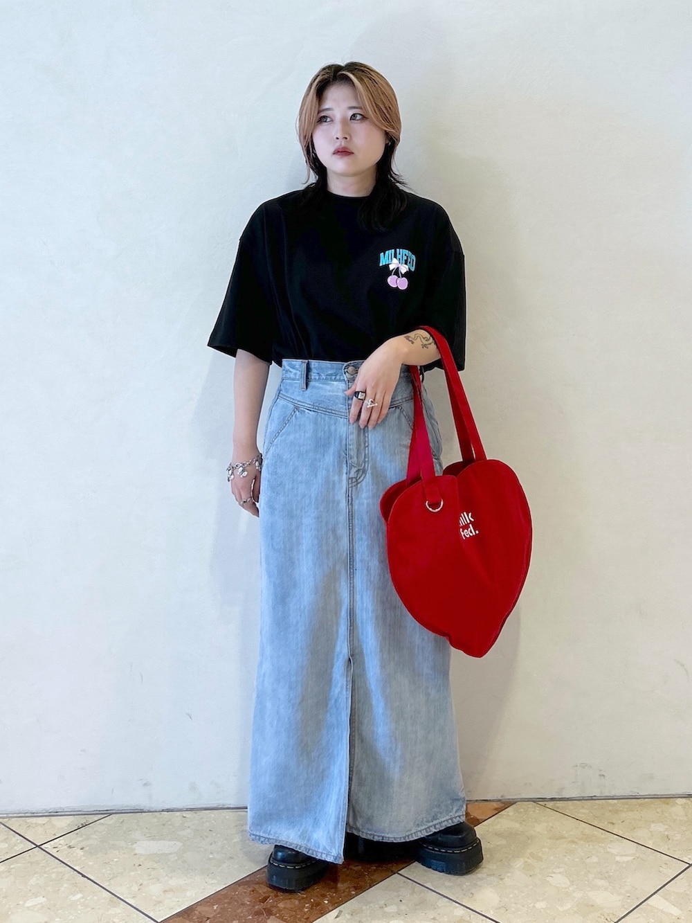 ブラック系のTシャツ/カットソー、ブルー系のデニムスカート、レッド系のトートバッグを着用したレディースの夏コーディネートの2枚目の写真