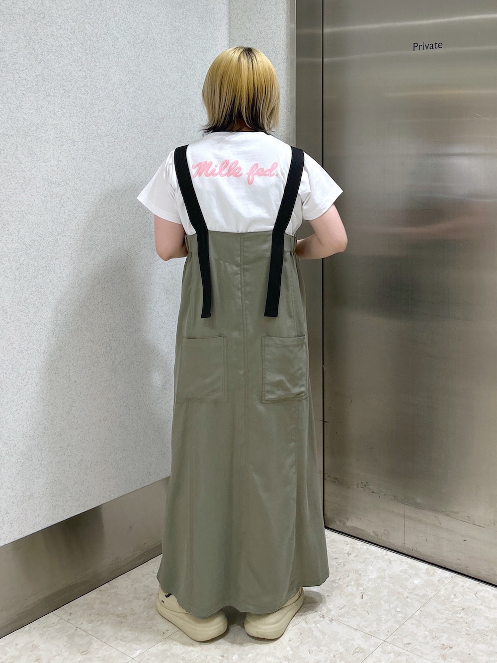 ブラック系のショルダーバッグ、ピンク系のTシャツ/カットソー、グリーン系のワンピースを着用したレディースの春コーディネートの4枚目の写真