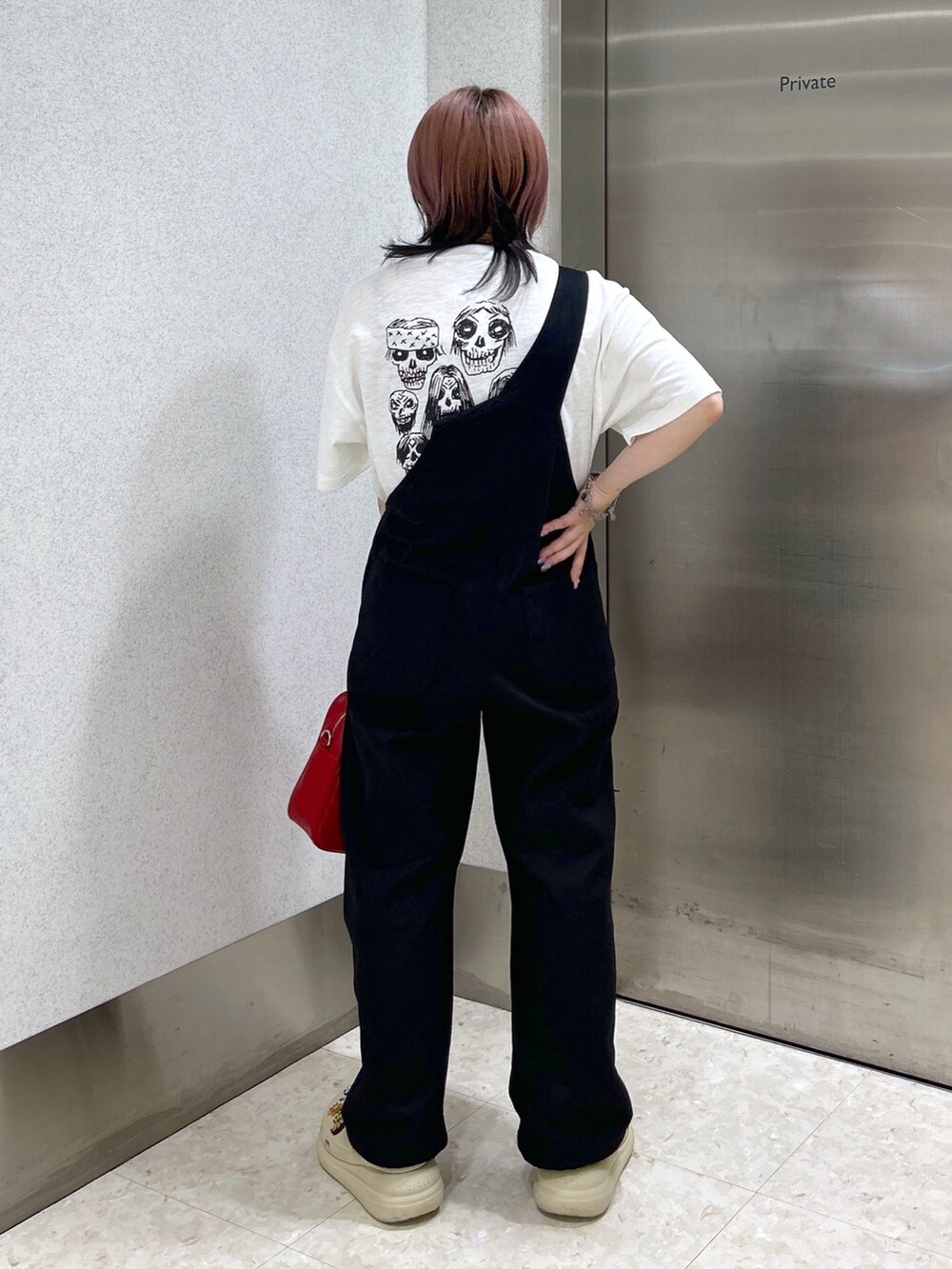 レッド系のショルダーバッグ、ブラック系のサロペット/オーバーオール、ホワイト系のTシャツ/カットソーを着用したレディースの春コーディネートの2枚目の写真