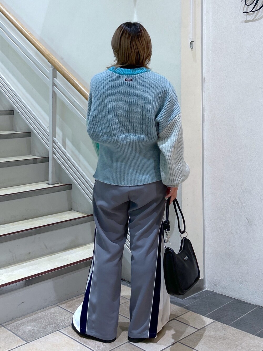 グリーン系のニット/セーター、ブラック系のショルダーバッグ、ブラック系のブーツを着用したレディースの冬コーディネートの4枚目の写真