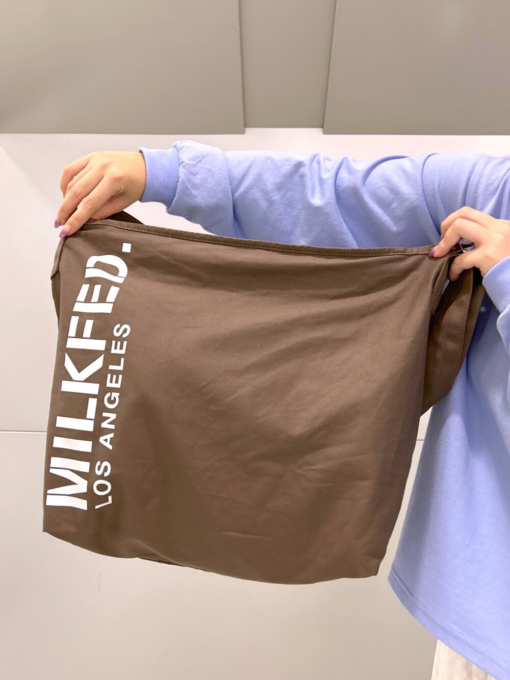 ブルー系のTシャツ/カットソー、ブラウン系のショルダーバッグ、ホワイト系のスカートを着用したレディースの夏コーディネートの4枚目の写真
