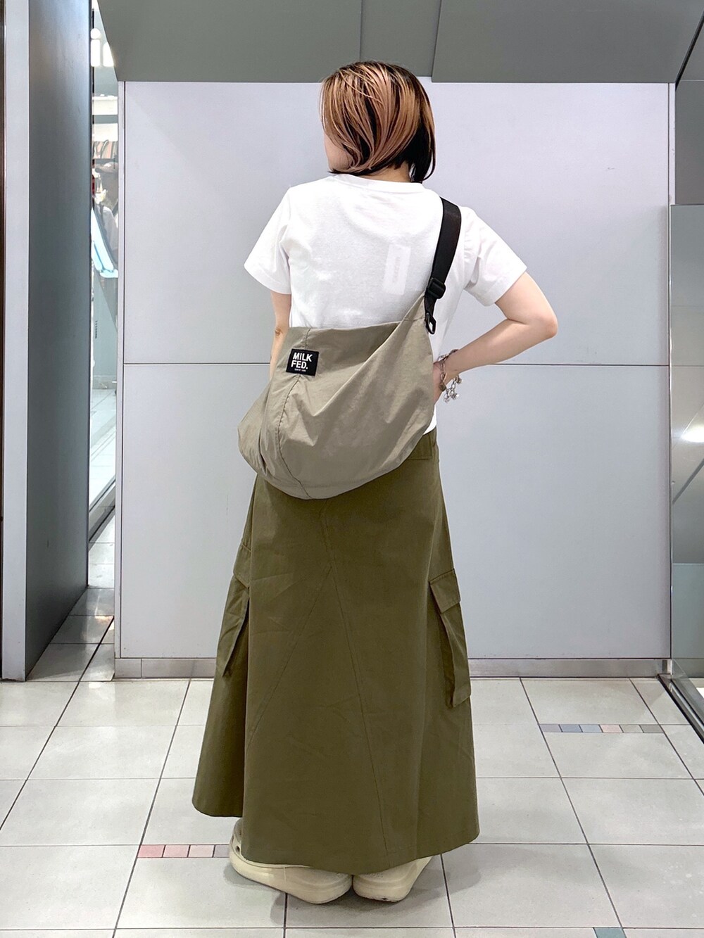 ベージュ系のサンダル、ベージュ系のショルダーバッグ、グリーン系のスカートを着用したレディースの夏コーディネートの2枚目の写真