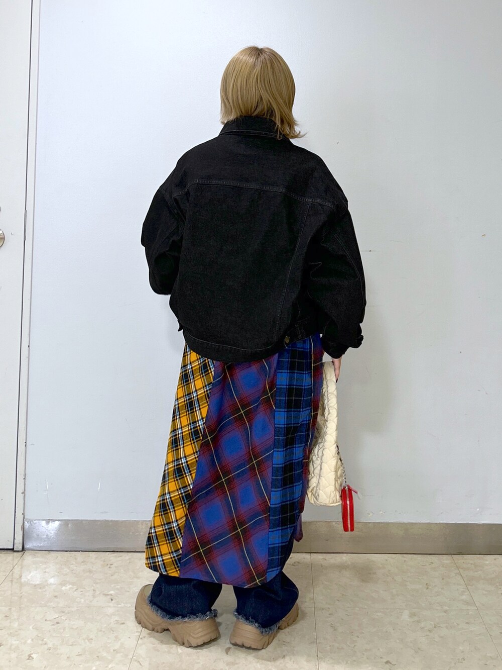 ブラック系のデニムジャケット、ブルー系のシャツワンピース、ホワイト系のハンドバッグを着用したレディースの秋コーディネートの3枚目の写真