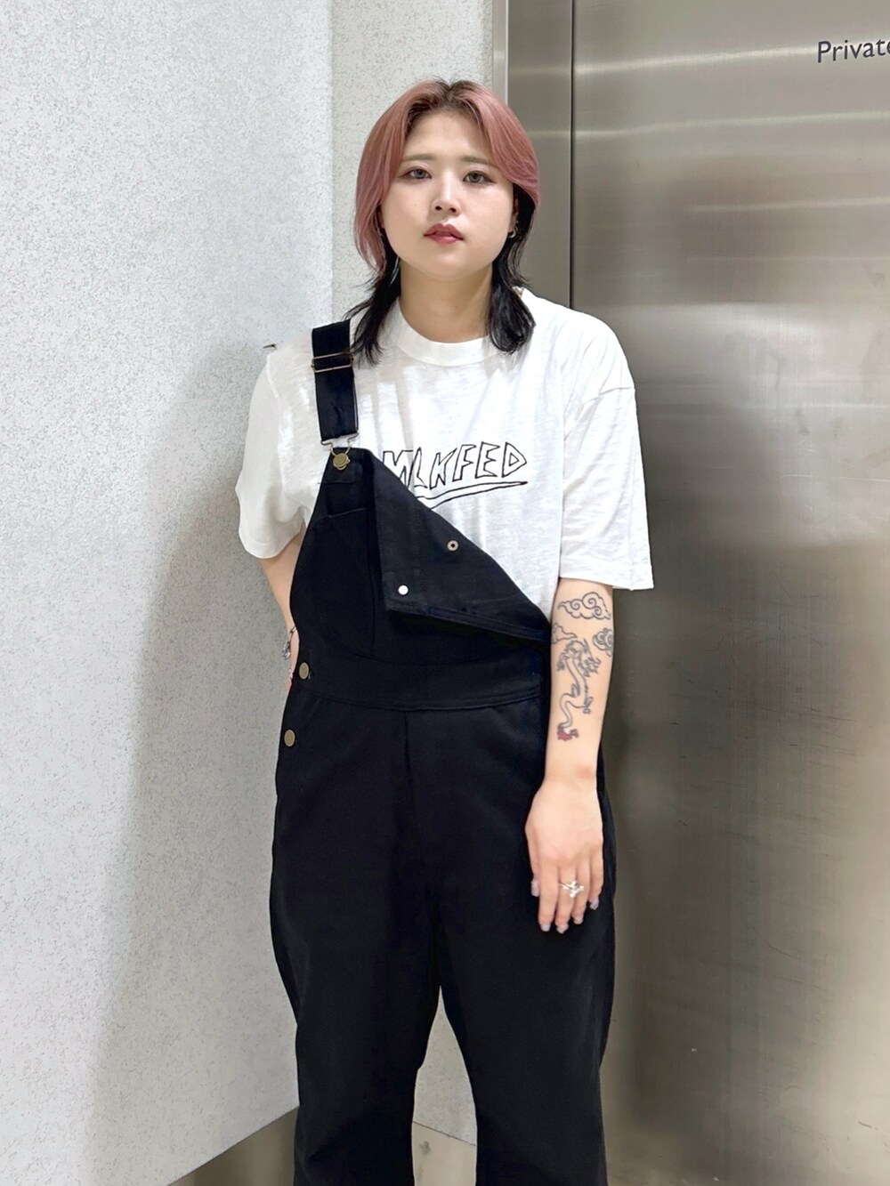 レッド系のショルダーバッグ、ブラック系のサロペット/オーバーオール、ホワイト系のTシャツ/カットソーを着用したレディースの春コーディネートの3枚目の写真