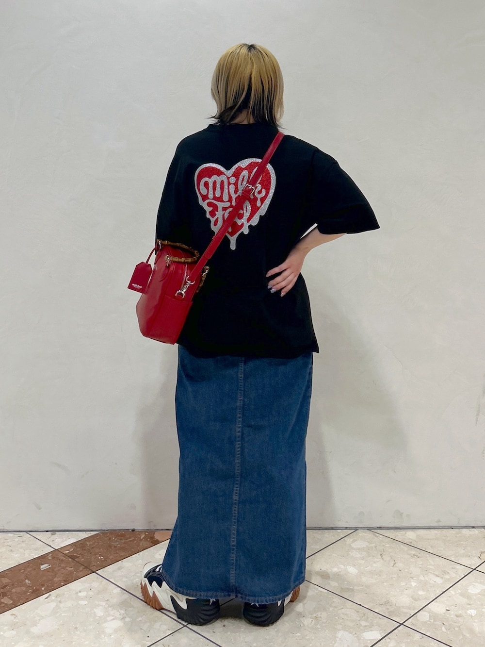 ブラック系のTシャツ/カットソー、レッド系のショルダーバッグ、ブルー系のデニムスカートを着用したレディースの春コーディネートの2枚目の写真