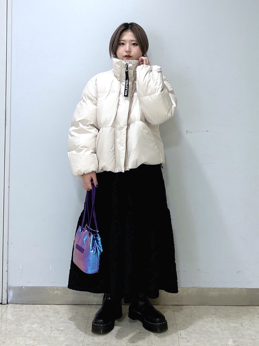 ホワイト系のダウンジャケット/コート、ブラック系のワンピース、パープル系のショルダーバッグを着用したレディースの冬コーディネートの2枚目の写真