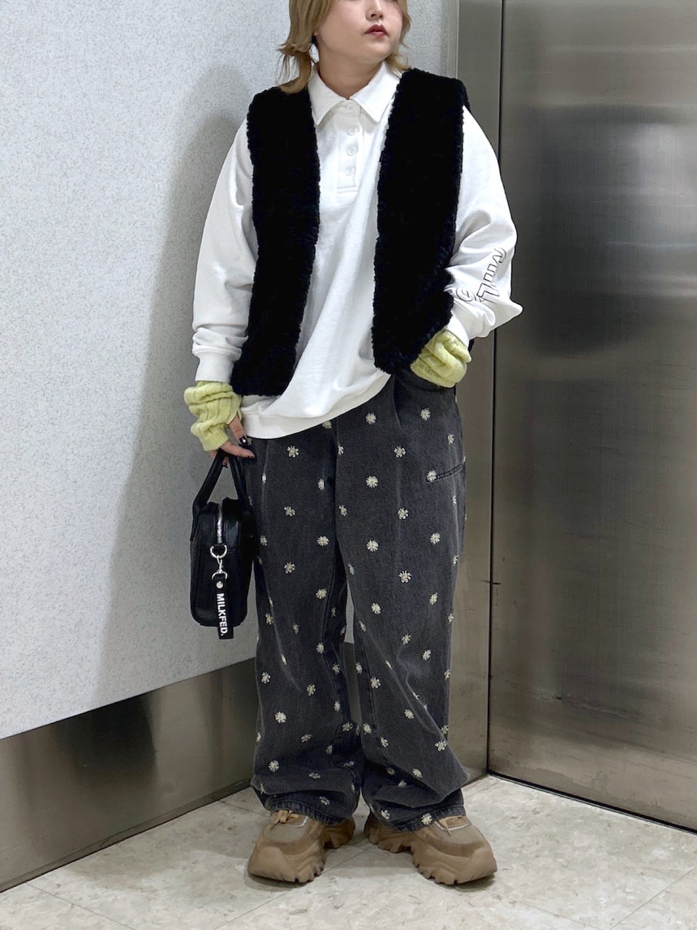 ブラック系のベスト、ホワイト系のスウェット、ブラック系のボストンバッグを着用したレディースの秋コーディネートの2枚目の写真