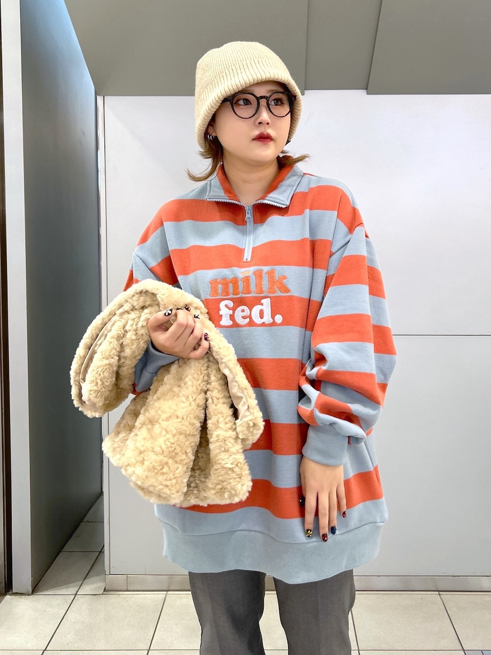 ホワイト系のベスト、ベージュ系のスニーカー、ピンク系のスウェットを着用したレディースの冬コーディネートの3枚目の写真