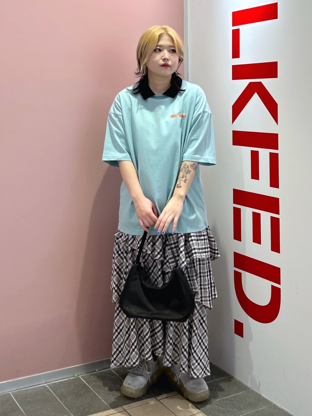 ブラック系のスカート、ブラック系のシャツ/ブラウス、グリーン系のTシャツ/カットソーを着用したレディースの春コーディネートの2枚目の写真