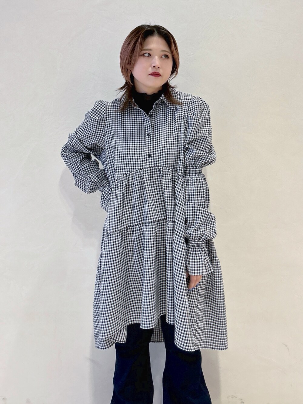 ブラック系のワンピース、ブルー系のデニムパンツ、ブラウン系のショルダーバッグを着用したレディースの春コーディネートの4枚目の写真