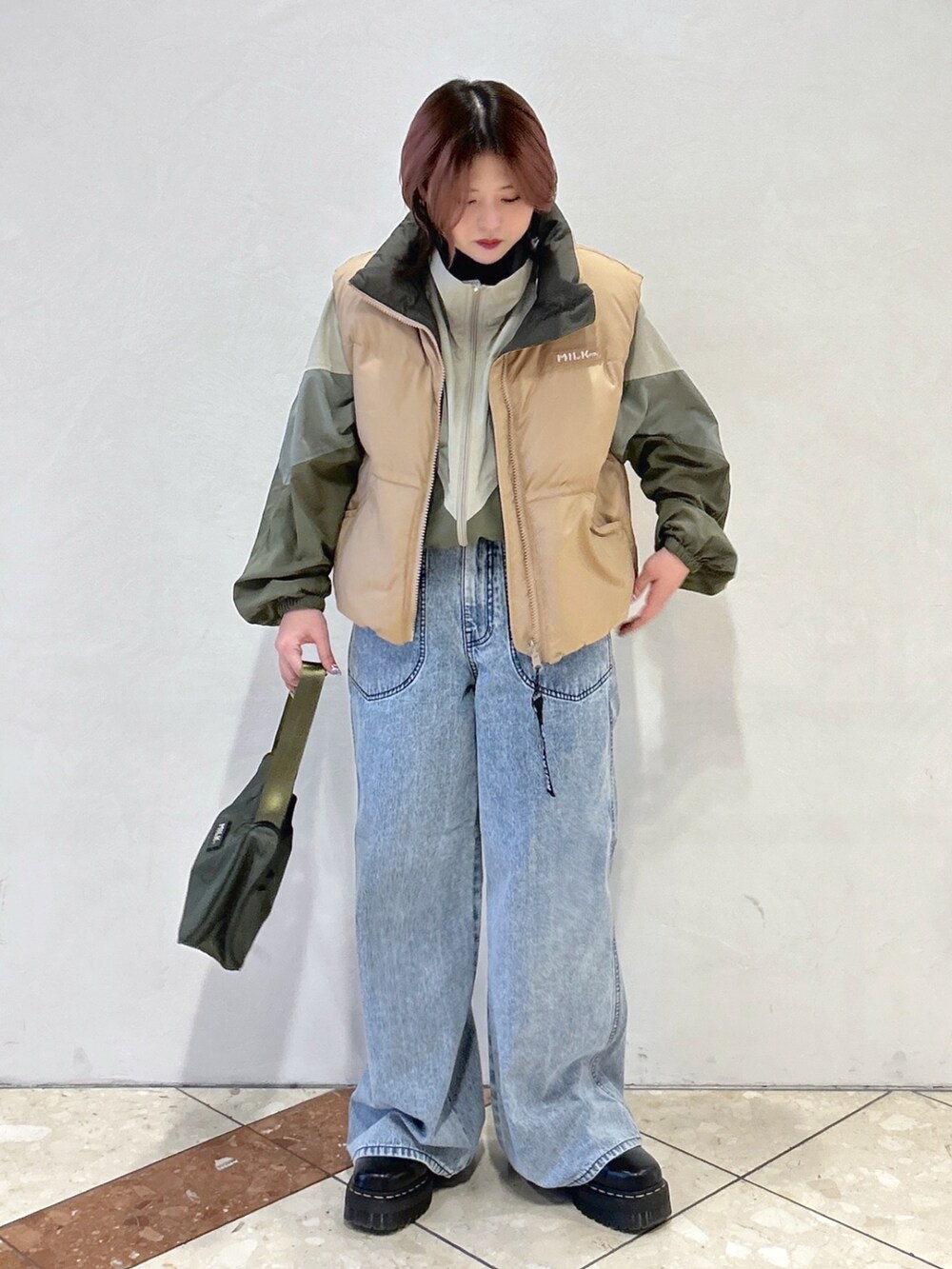 ブルー系のデニムパンツ、グリーン系のハンドバッグ、ブラック系のブーツを着用したレディースの冬コーディネートの2枚目の写真