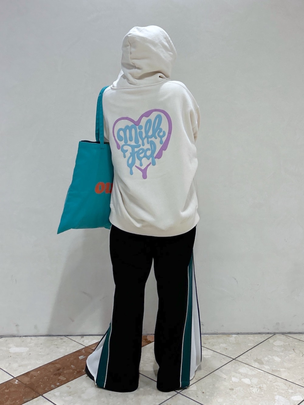 ホワイト系のパーカー、ブラック系のその他パンツ、グリーン系のトートバッグを着用したレディースの春コーディネートの3枚目の写真