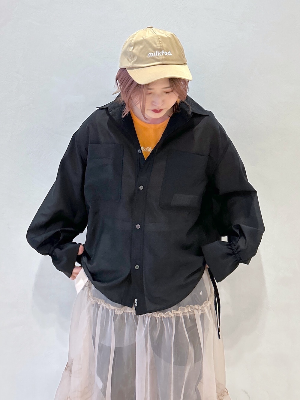 オレンジ系のTシャツ/カットソー、ブラック系のシャツ/ブラウス、ベージュ系のスカートを着用したレディースの冬コーディネートの5枚目の写真