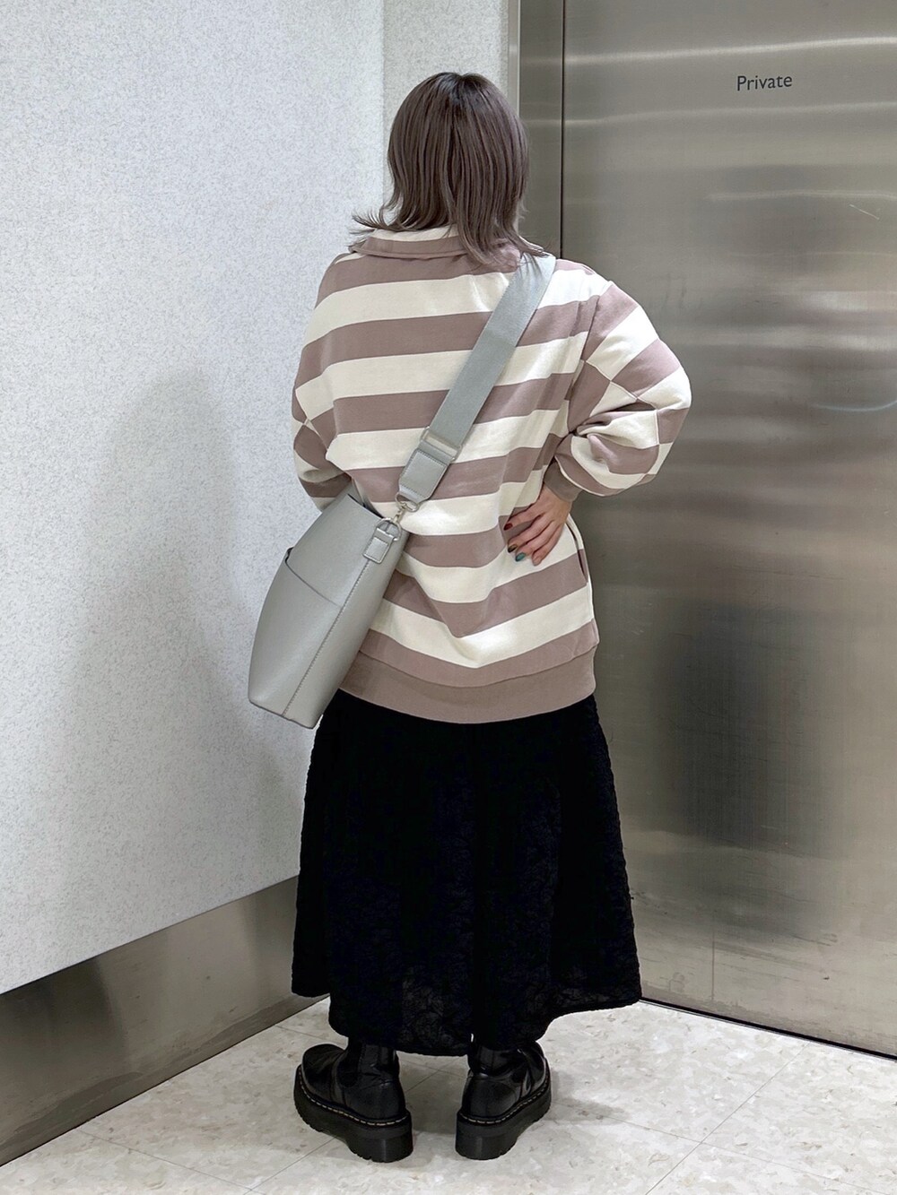 グレー系のスウェット、ブラック系のワンピース、ブラック系のブーツを着用したレディースの冬コーディネートの2枚目の写真