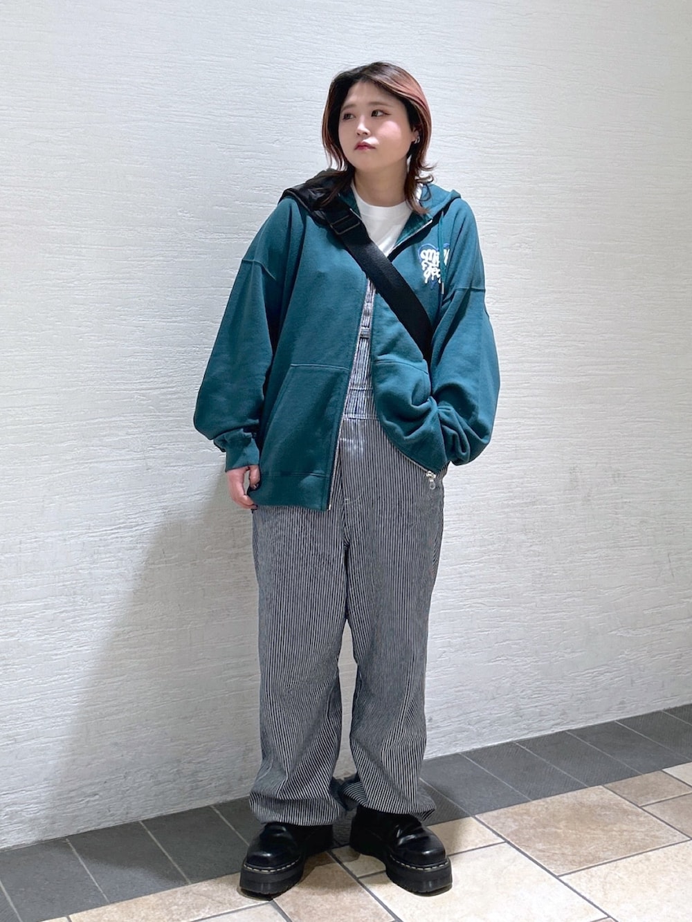 グリーン系のパーカー、その他のサロペット/オーバーオール、ブラック系のメッセンジャーバッグを着用したレディースの春コーディネートの2枚目の写真