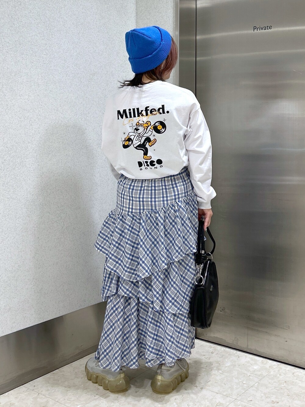 ホワイト系のTシャツ/カットソー、ブルー系のスカート、ブラック系のショルダーバッグを着用したレディースの冬コーディネートの2枚目の写真